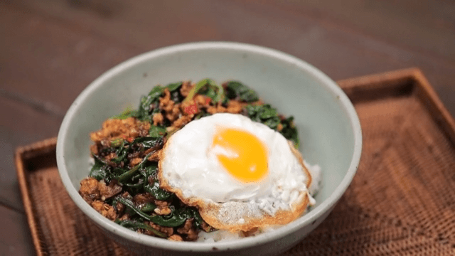 Bowl of rice topped with fried egg and spinach