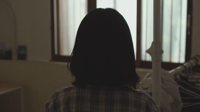 Woman standing and looking out of the window in a dim room