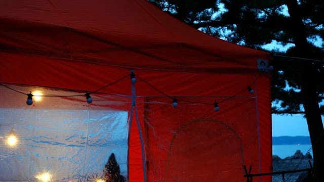 Orange tent decorated with bulb lights at dusk