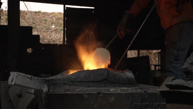 Worker stoking a furnace in a dimly lit workshop