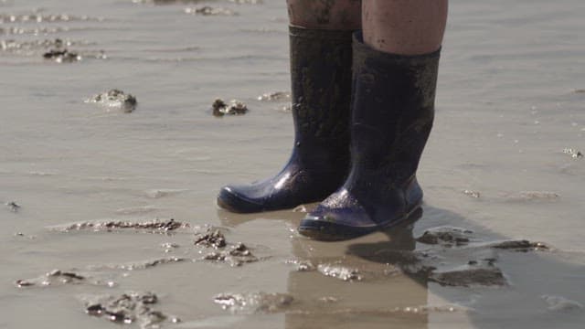 Person Running on a Mudflat Wearing Boots