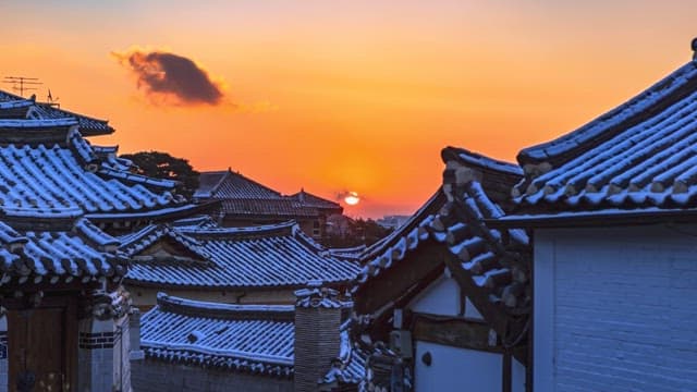 View of the rising sun from a snow-covered Bukchon Hanok Village