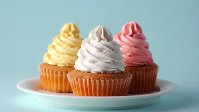 Cupcakes being decorated with colorful sprinkles