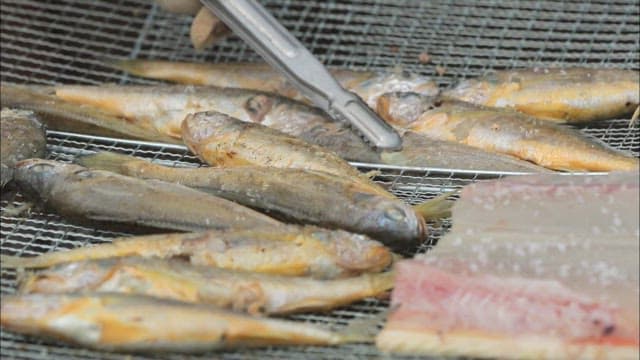 Crispy grilled yellow croaker on an outdoor grill