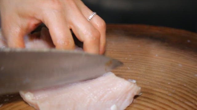 Slicing raw beef tripe on a wooden board