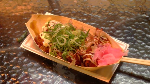 Delicious takoyaki dish garnished with vibrant toppings placed on a glass table