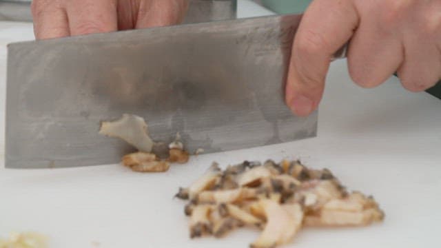 Cutting a abalone with a knife on a white cutting board