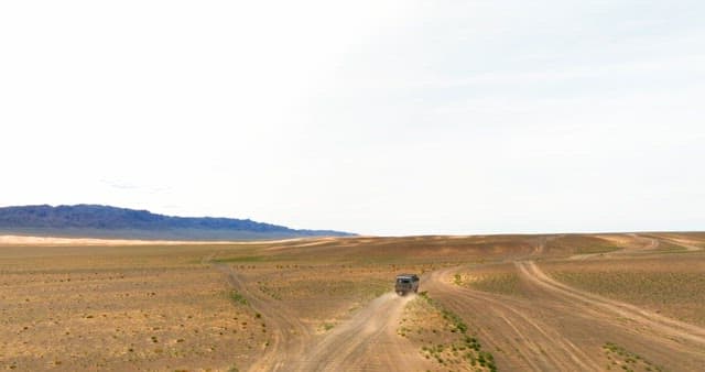 Vehicle driving through a vast desert landscape