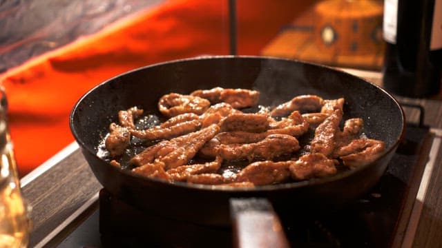 Grilling sizzling meat on a hot frying pan with oil