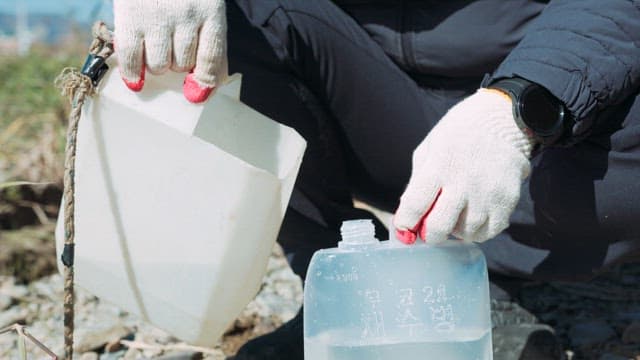 Pouring Water into a Sampling Bottle to Test Water Quality