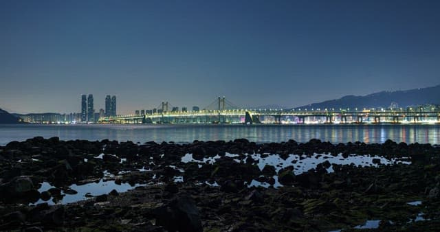 Cityscape from night to dawn with bridge and quiet beach
