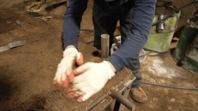 Worker shaping sand in a workshop