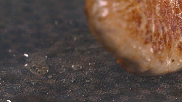 Piece of meat sizzling on a grill